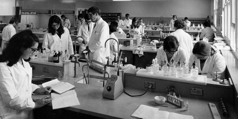 Students standing in a lab - play video