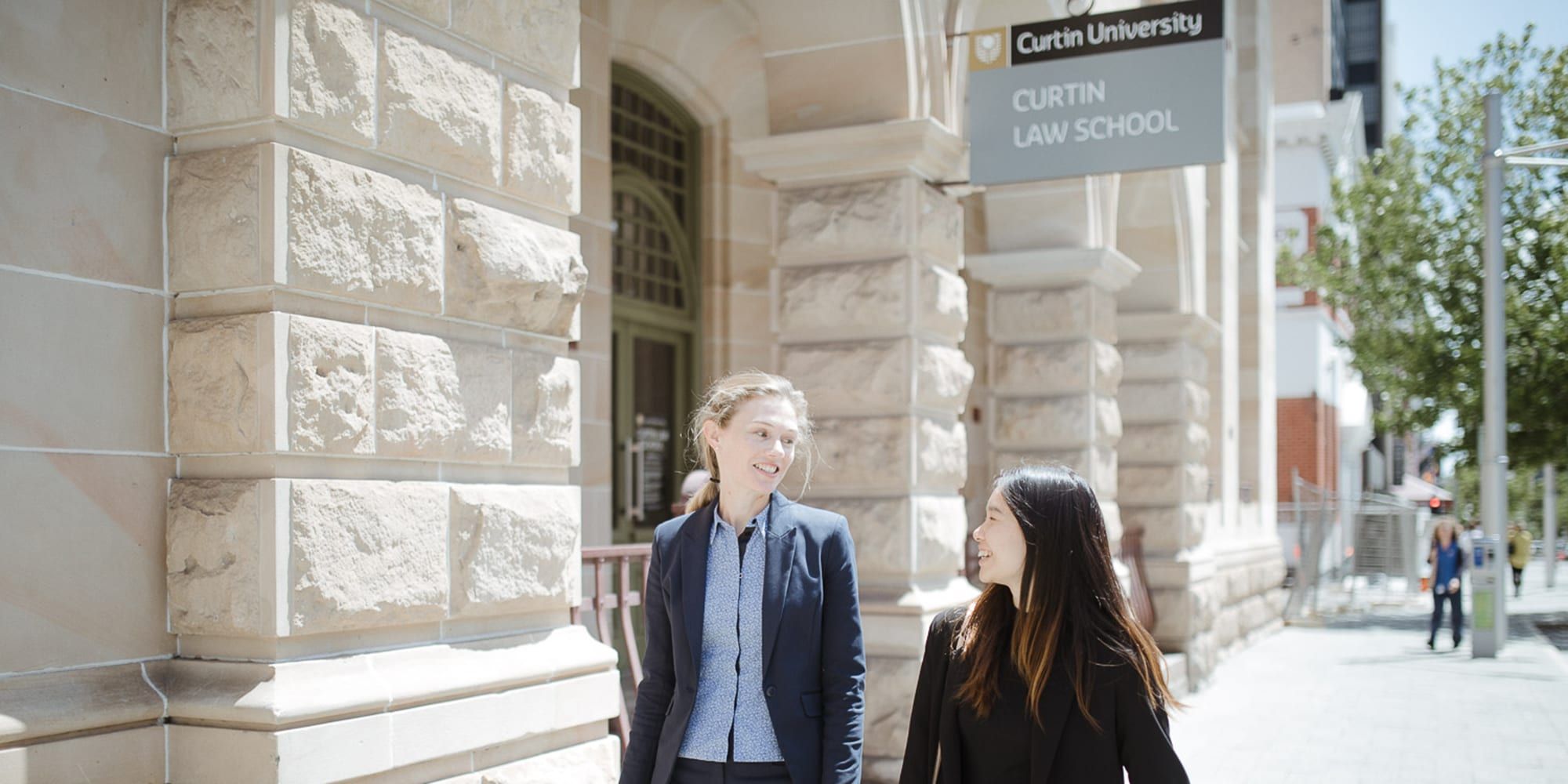 Students walking in front of the Curtin Law School building - play video