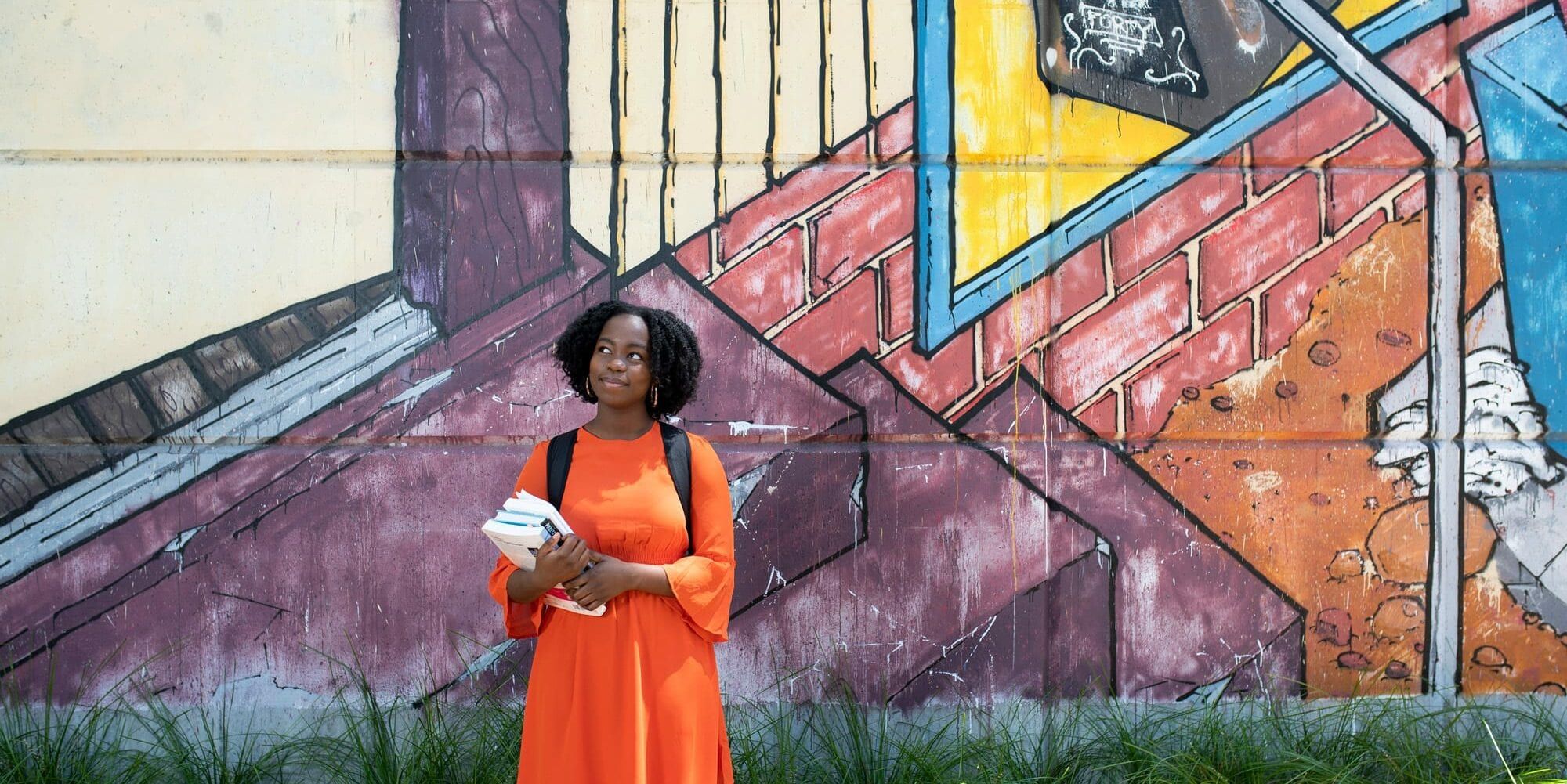 Student standing near wall containing street art - play video