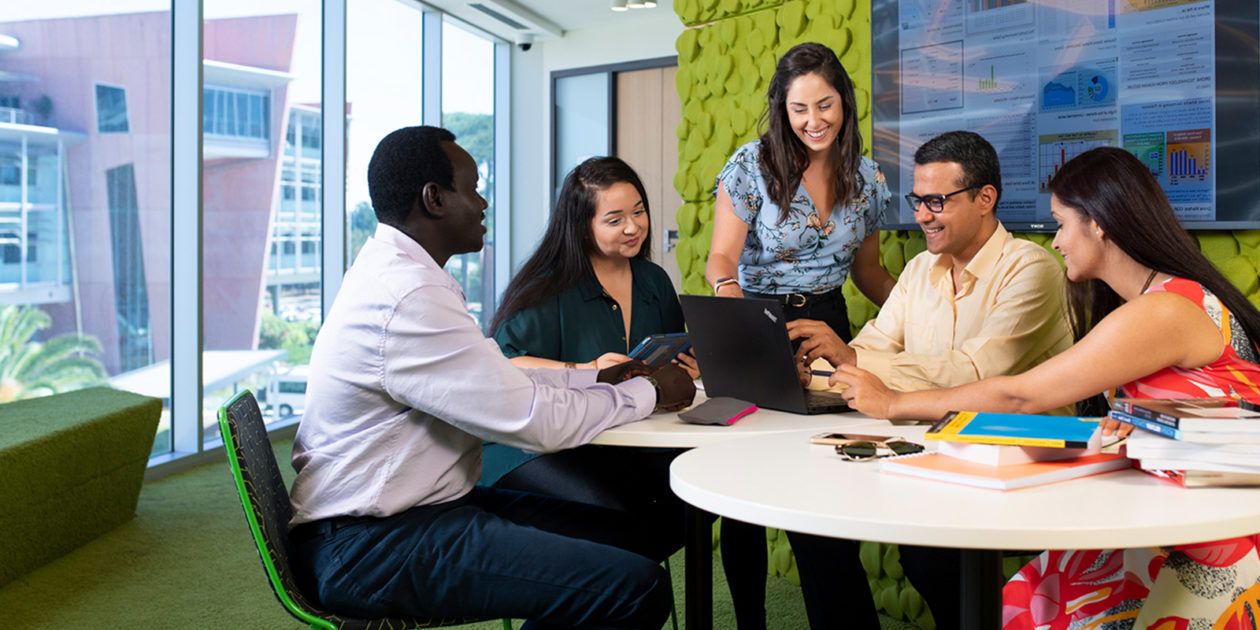 A group of students meeting and looking and information on a laptop