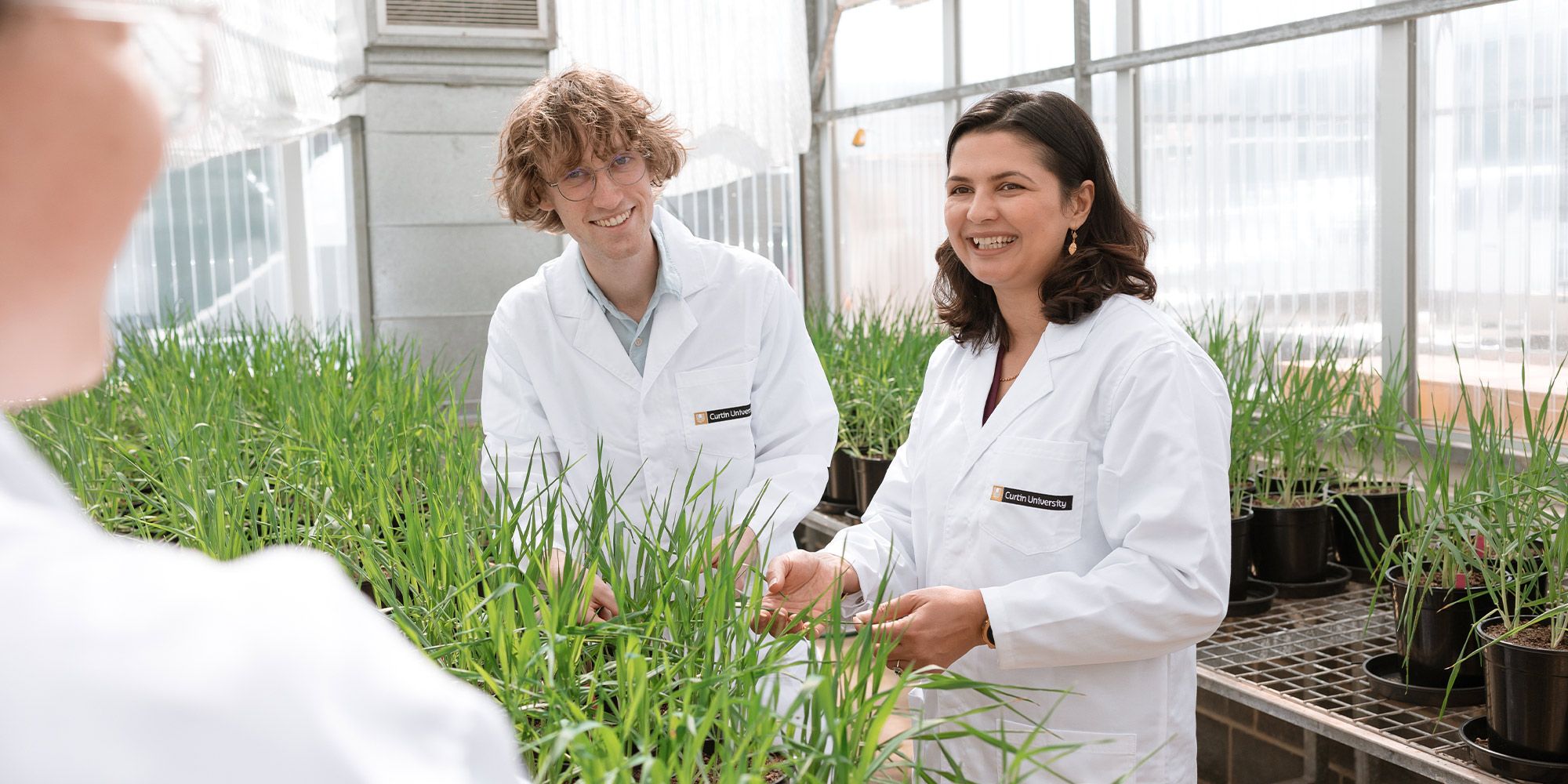 People wearing lab coats working with plants in an agriculture lab grow space