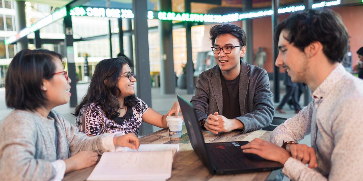 Students sitting outside, discussing a project