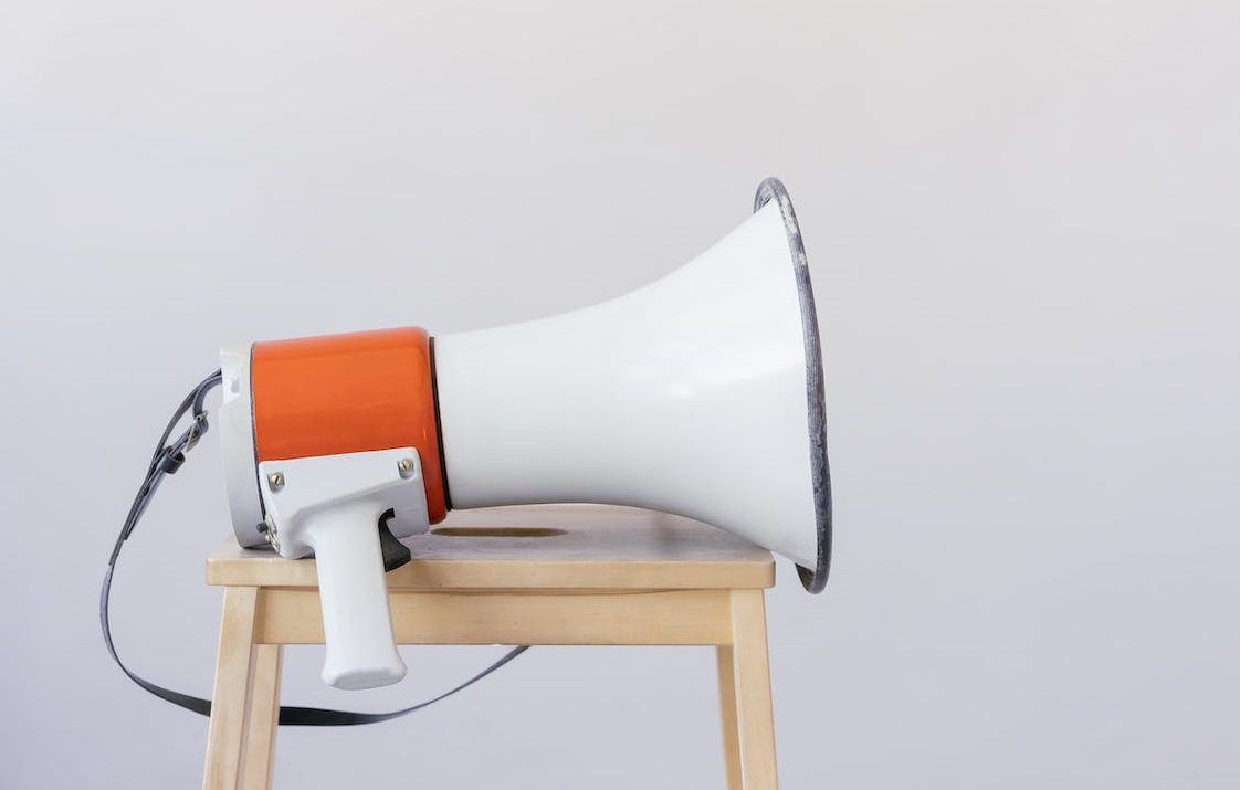 Megaphone sitting on a wooden stool in front of a plain backdrop