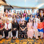 A large group of women sit together for a group photo beside pull up banners for the Vietnam Australia Centre