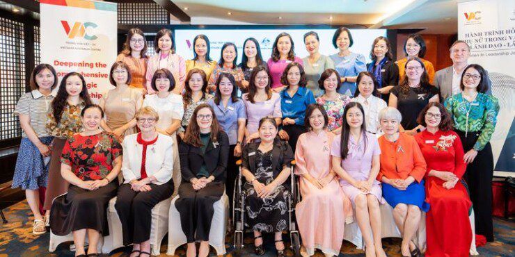 A large group of women sit together for a group photo beside pull up banners for the Vietnam Australia Centre