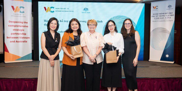 Five women standing together in front of a display screen showing the logo for Vietnam Australia Centre