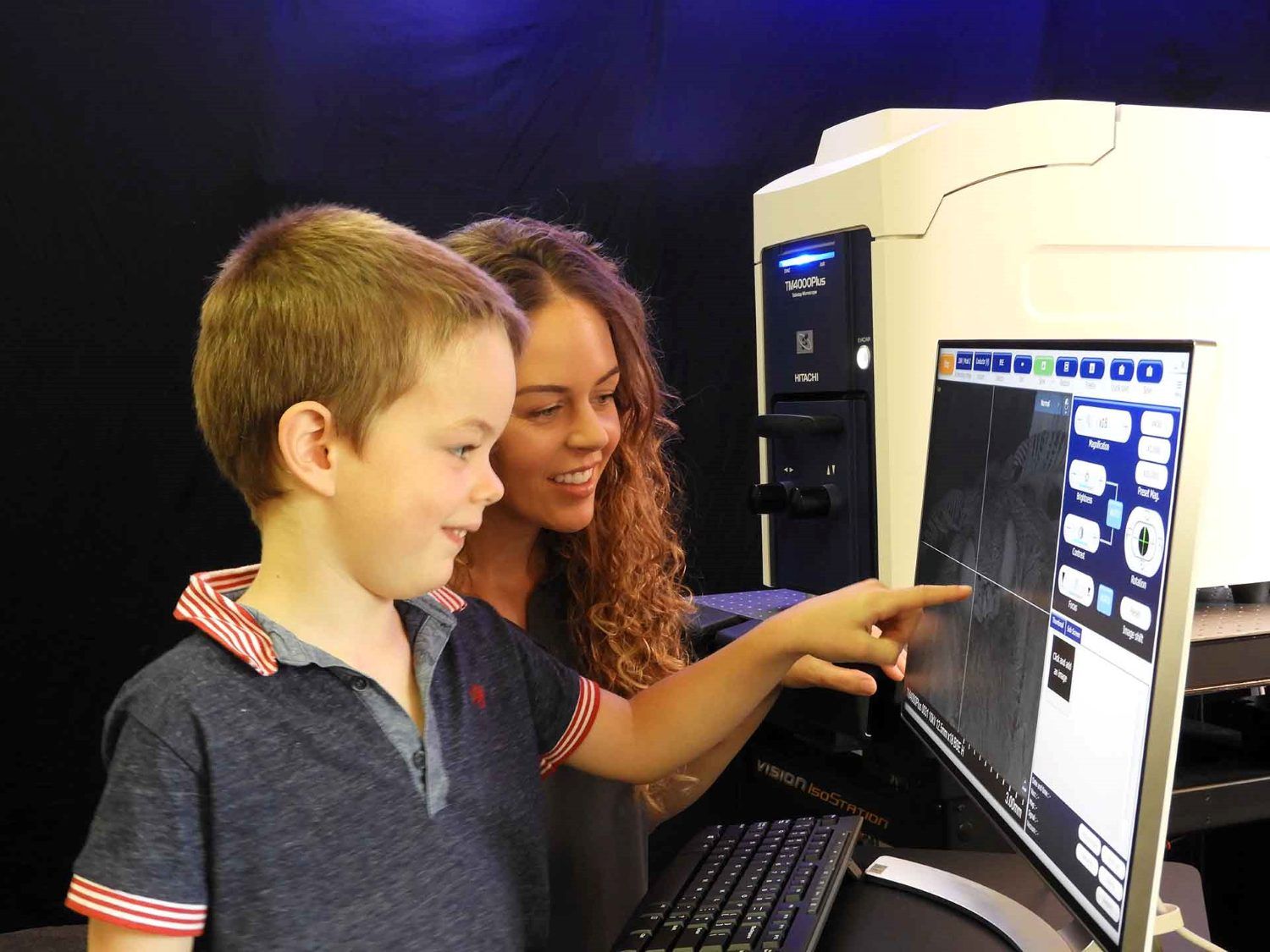 Child and adult looking and pointing at a screen with a close up image