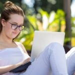 A female student sitting on a beanbag works on her laptop