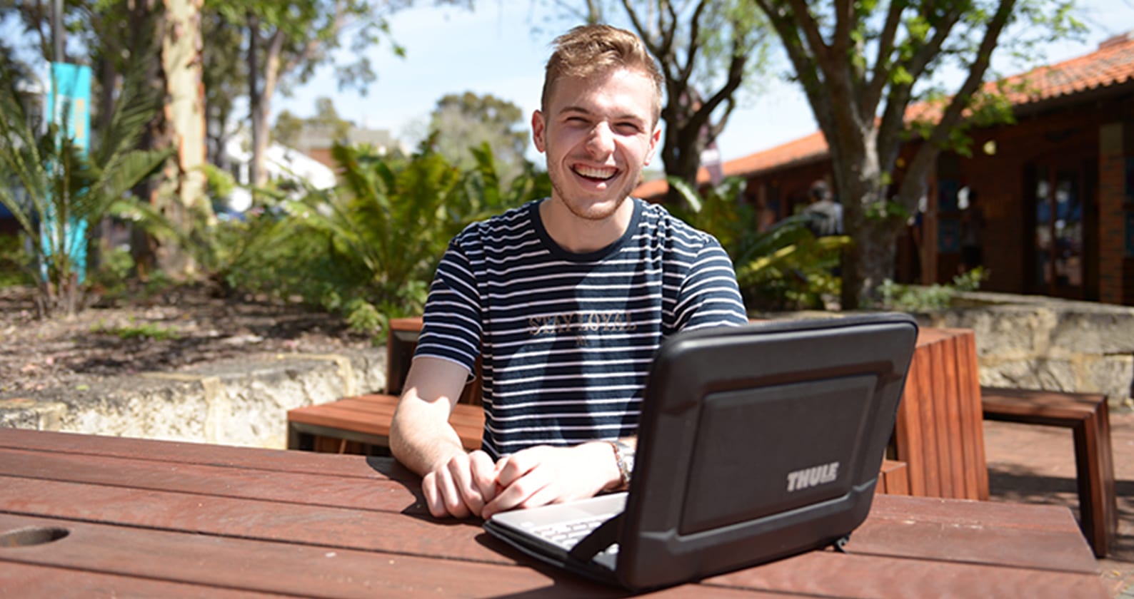 Student sitting outdoors with a laptop.