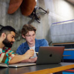 2-students-sitting-together-looking-at-a-laptop