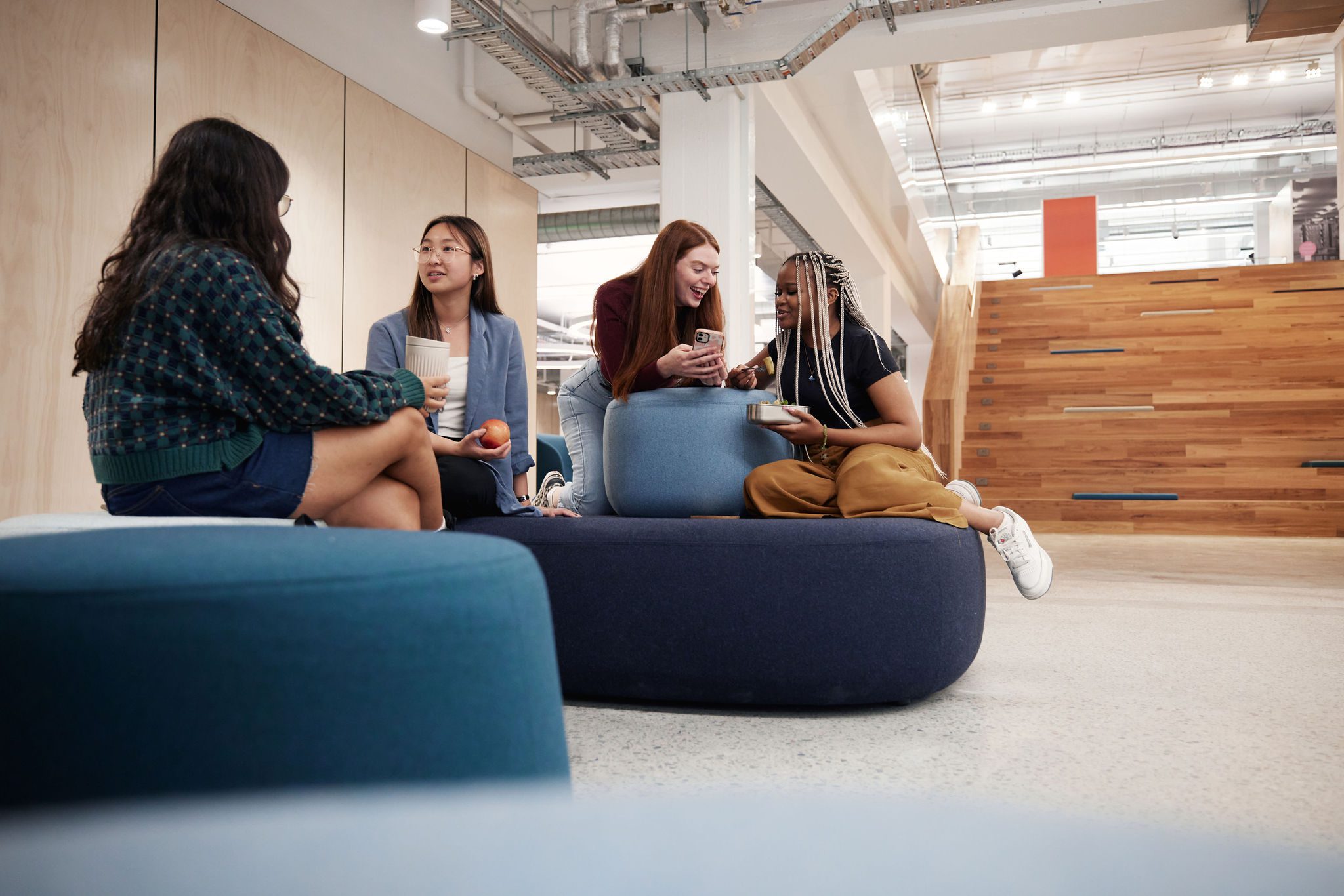 Students sitting on casual furniture in the library foyer chatting.