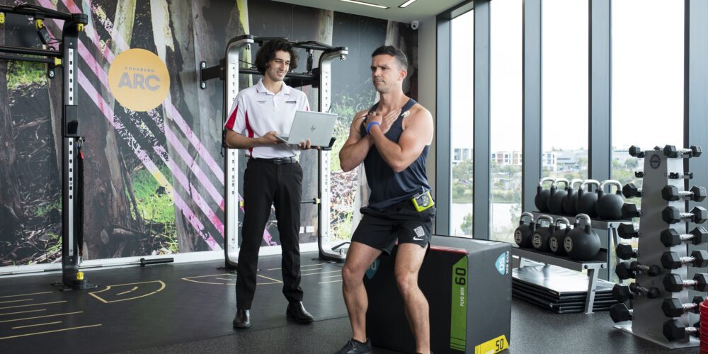 Male health sciences student assesses the fitness of a male client in a gymnasium