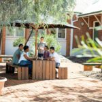 A group of students sitting at a table underneath an umbrella on the Curtin Kalgoorlie campus.