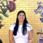 Shayera smiles in front of a Curtin Kalgoorlie mural.