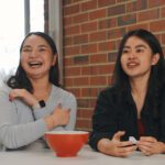 Celena and Devna sit at a table selecting questions out of a bowl.