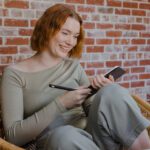 Student sitting in a chair holding an iPad and pen.