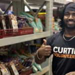 Curtin Kalgoorlie student and Curtin Volunteer! gives a thumbs up to the camera whilst working at Food Bank.