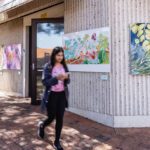 Students walking outside a building with art on the walls.