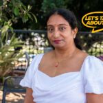 Yamini a mature aged student smiles wearing a white dress and red lipstick.