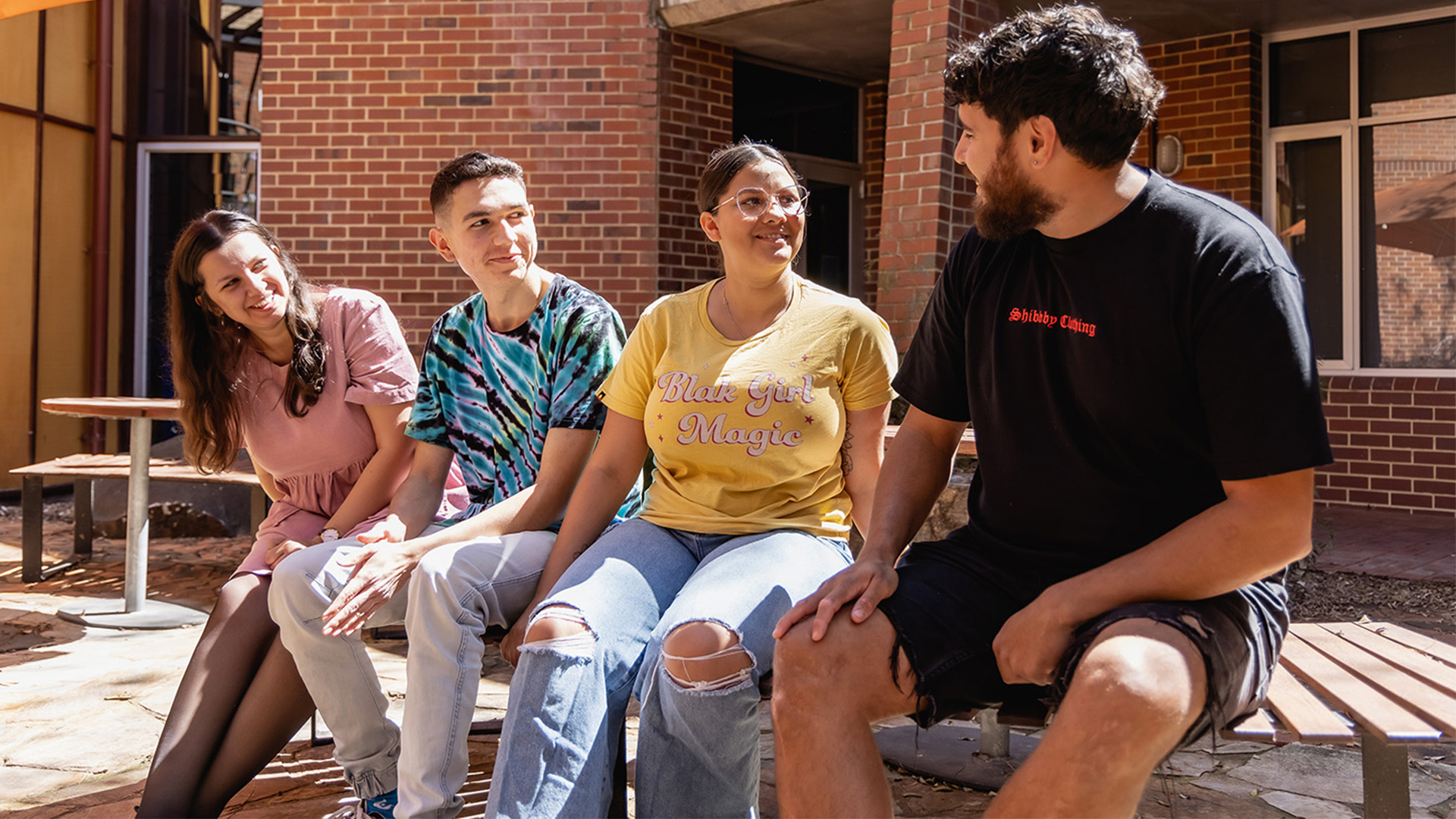 Four students sitting outside the Centre for Aboriginal Studies building