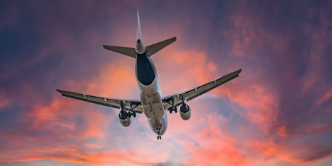 Aeroplane flying against a cloudy sunset sky.