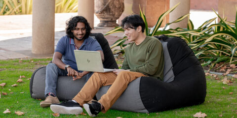 Two students looking at a laptop while sitting on beanbags.