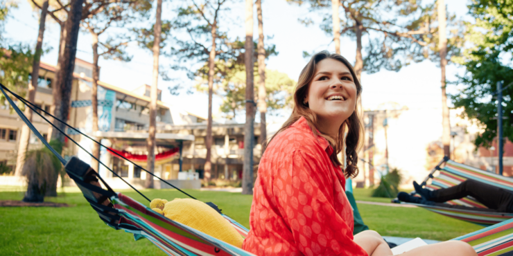 Student smiles whilst sitting on a hammock