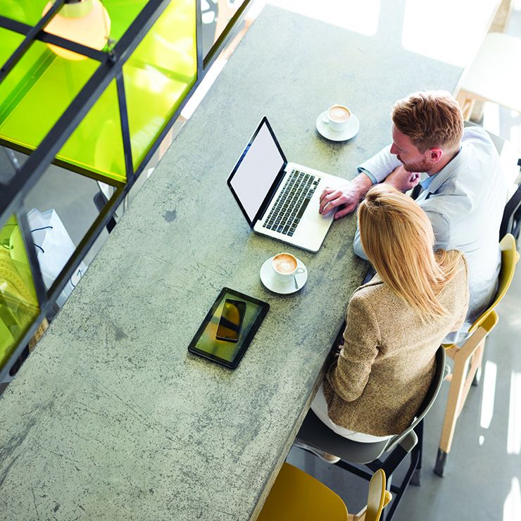 Aerial view of a male and female sitting at a cafe table with a laptop open in front of them