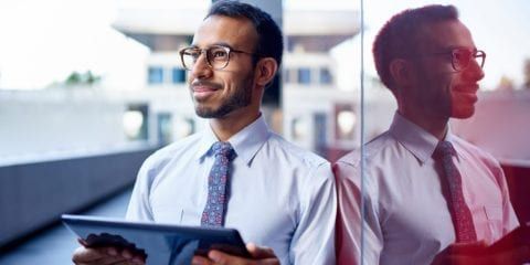 businessman holding an ipad looking out to the view