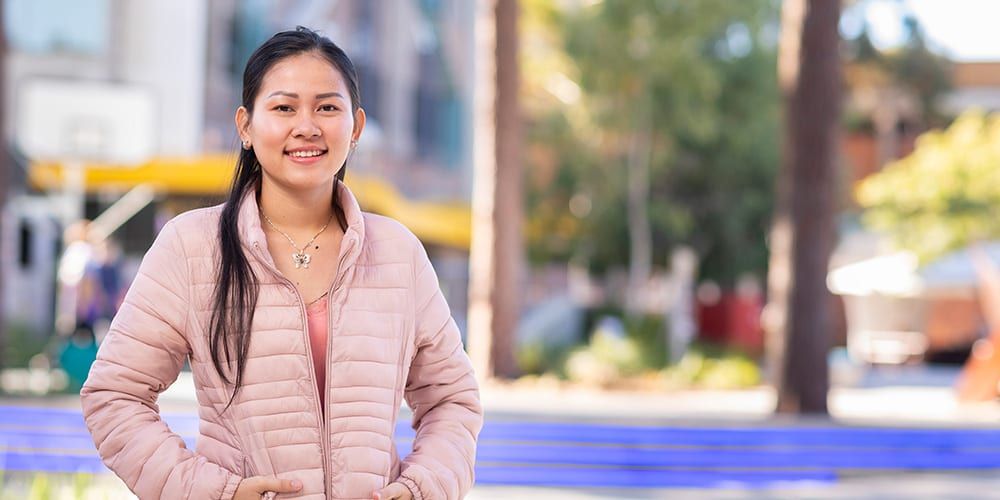 Female student wearing pink jacket smiling at camera