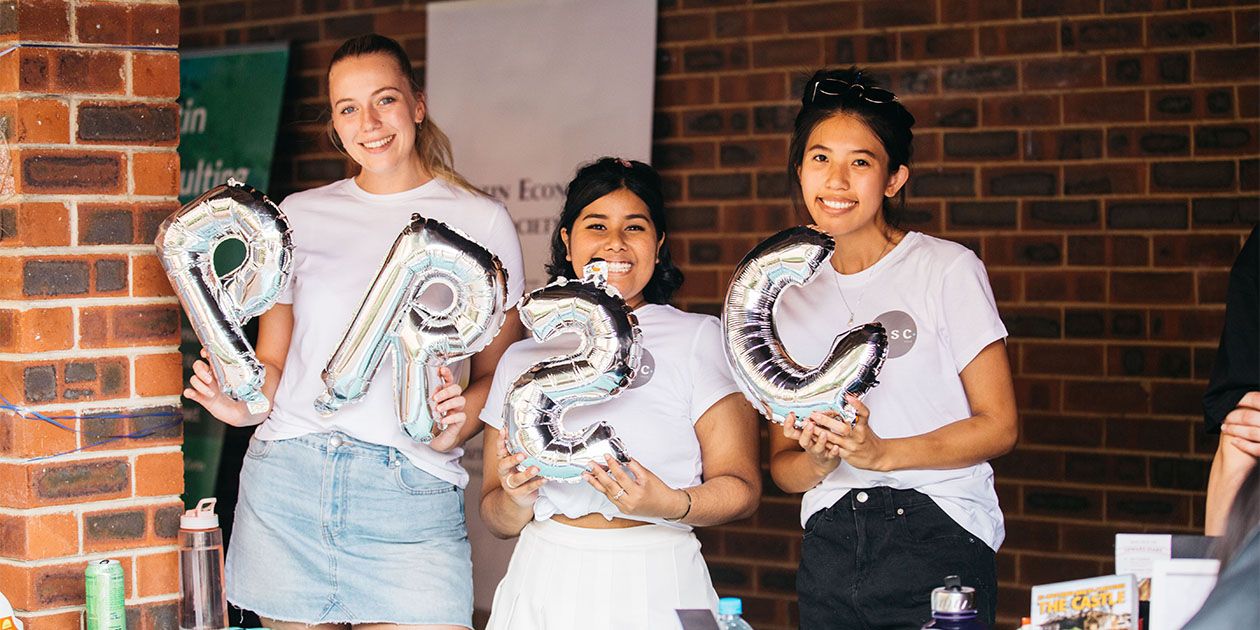 Three students holding up balloons