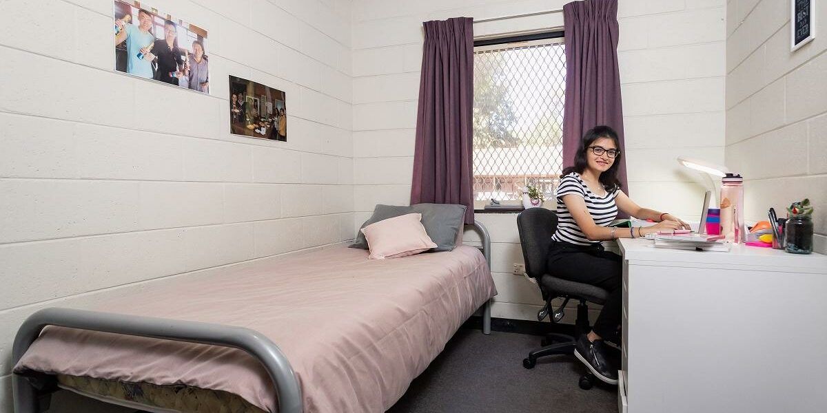 Student working on a laptop in guild house bedroom