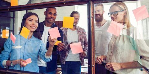 Business people meeting at office and use post it notes to share idea. Brainstorming concept. Sticky note on glass wall.