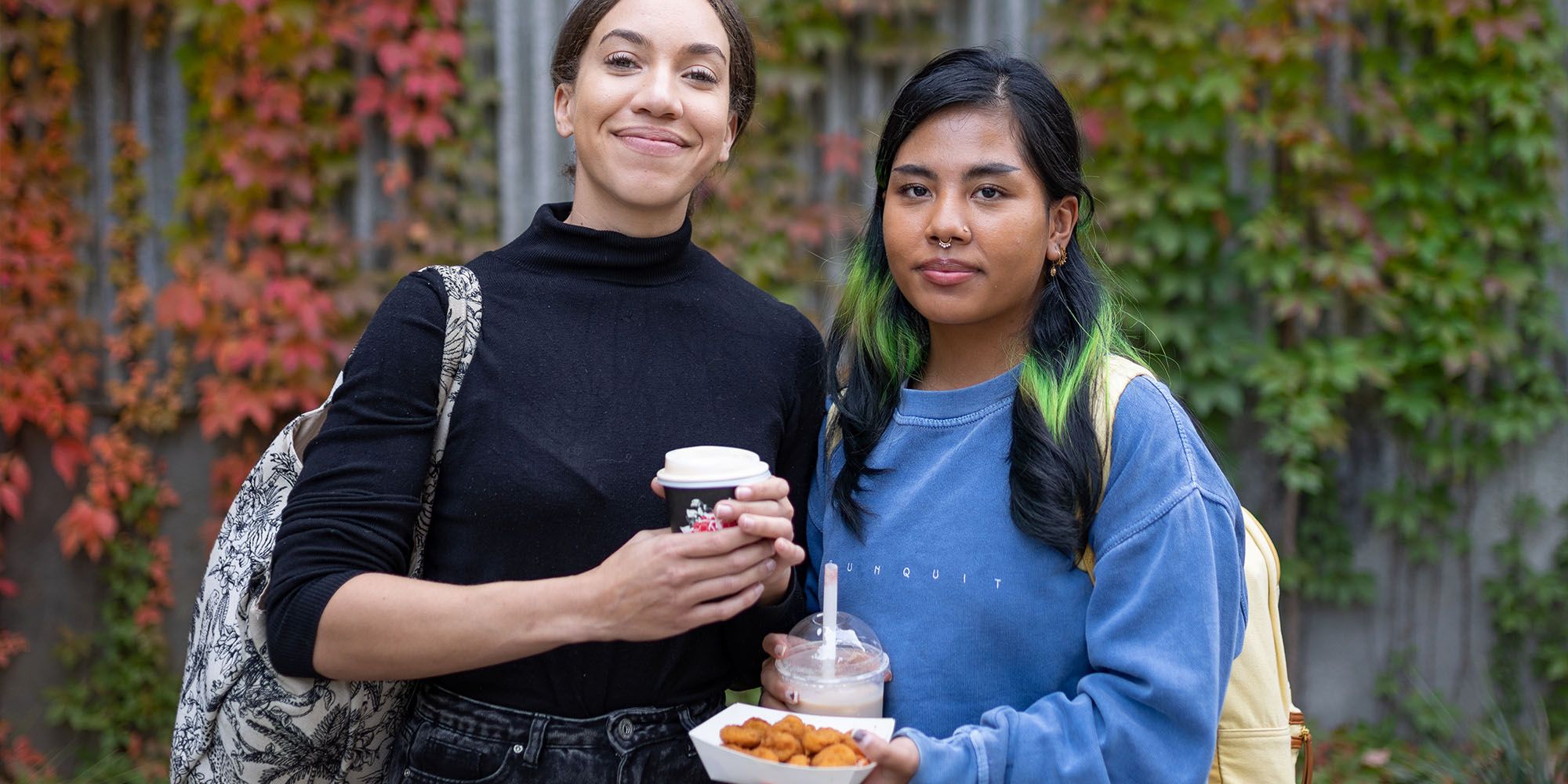 Two students with food and drinks from the food trucks