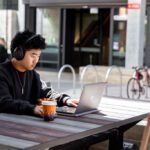 Student drinking a coffee and working on their laptop