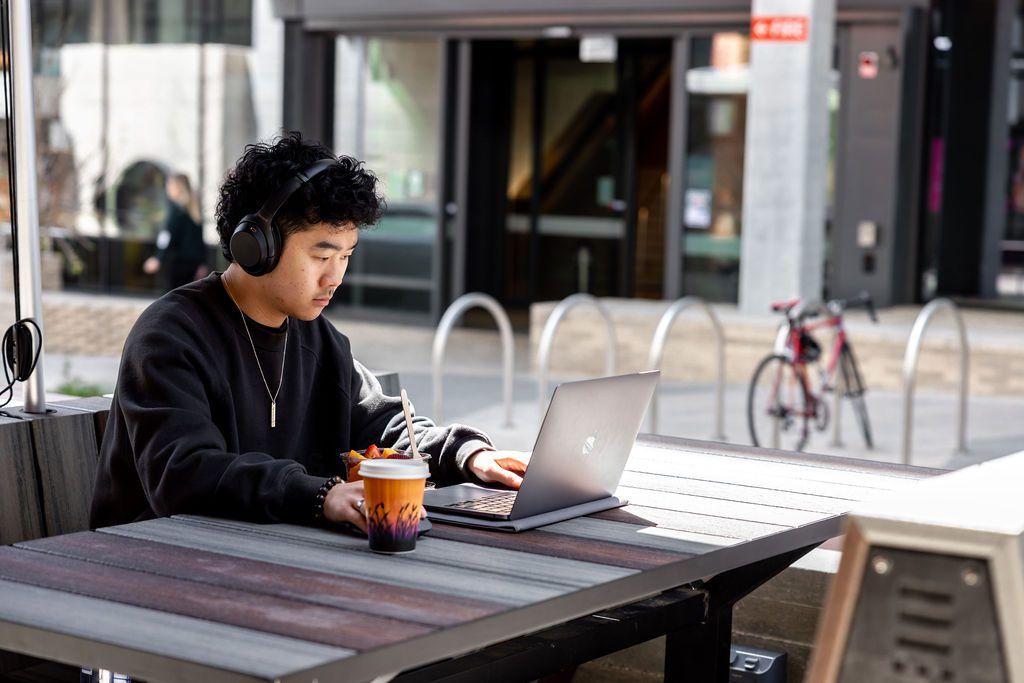 Student drinking a coffee and working on their laptop