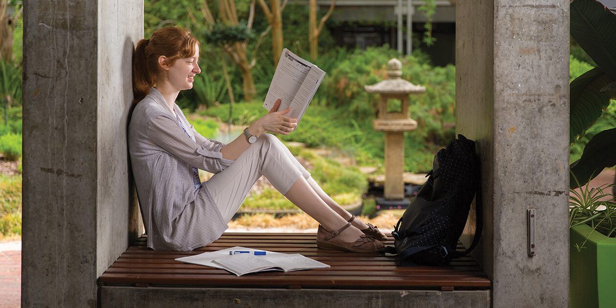 Student reading coursework in the Japanese Garden at Curtin