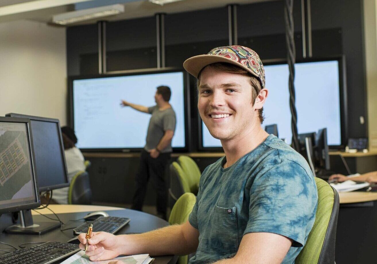 student wearing a cap sitting at a computer desk