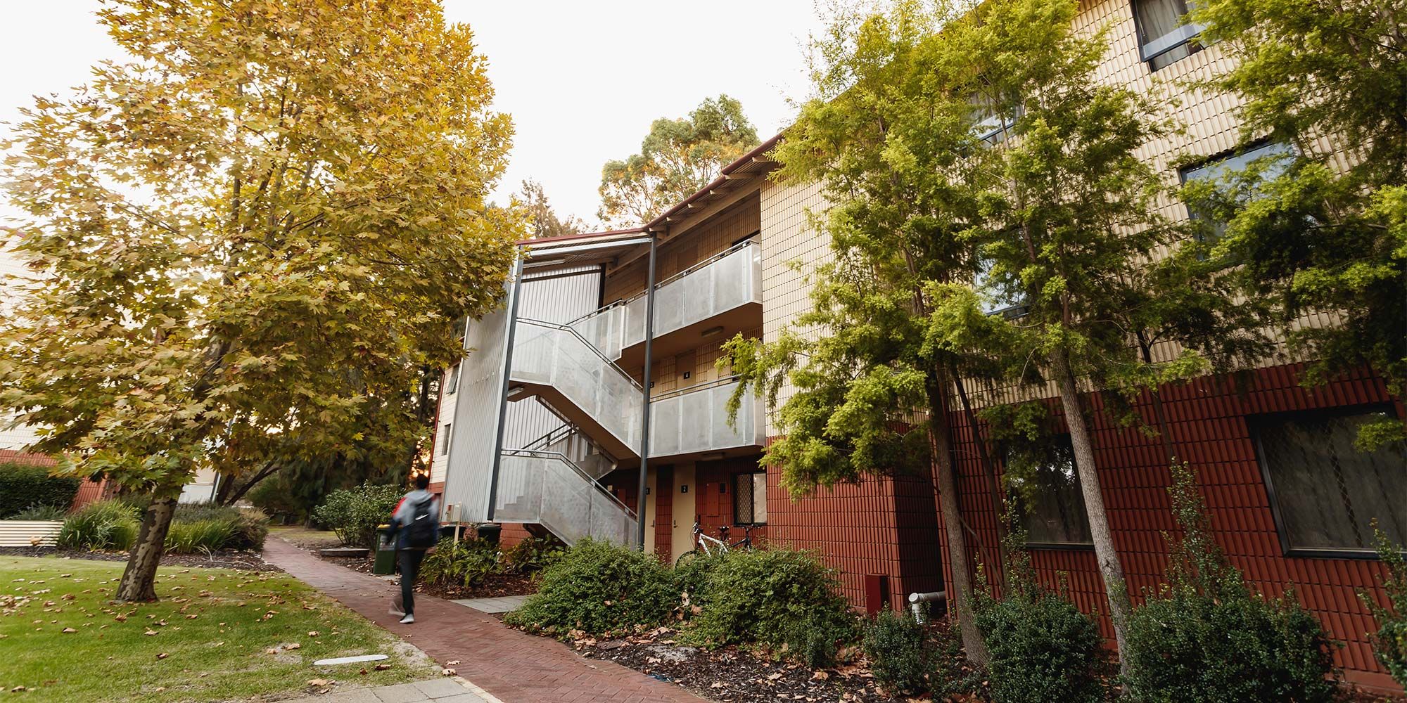 Outside of Guild House student accomodation. Guild house is shown to be three stories high with a number of trees and greenery outside.