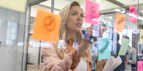 Female adding post-it notes to an office window.