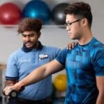 Physiotherapy student showing shoulder exercises to patient