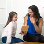 Speech pathologist showing something on an ipad to a little patient