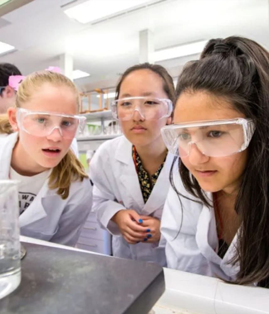 Students with safety glasses on looking at a beaker