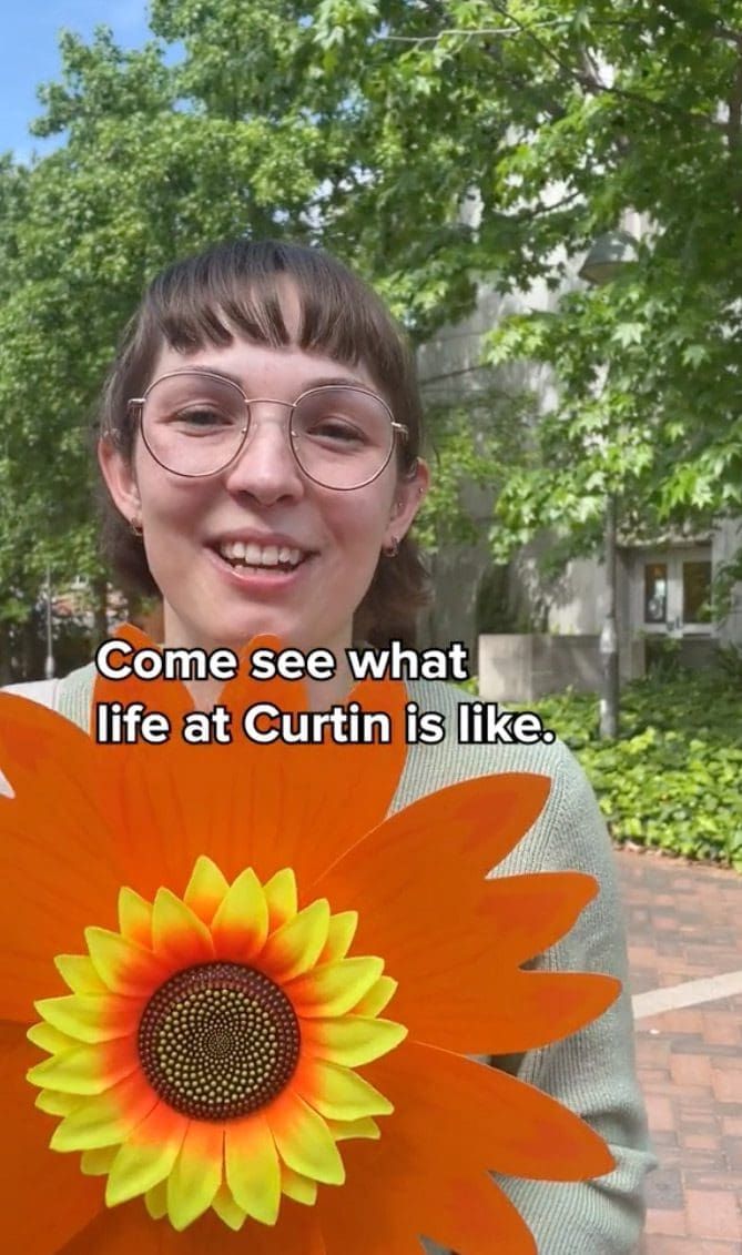 Girl with a huge orange flower in front of her