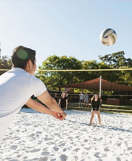 Students playing volleyball on a sunny day