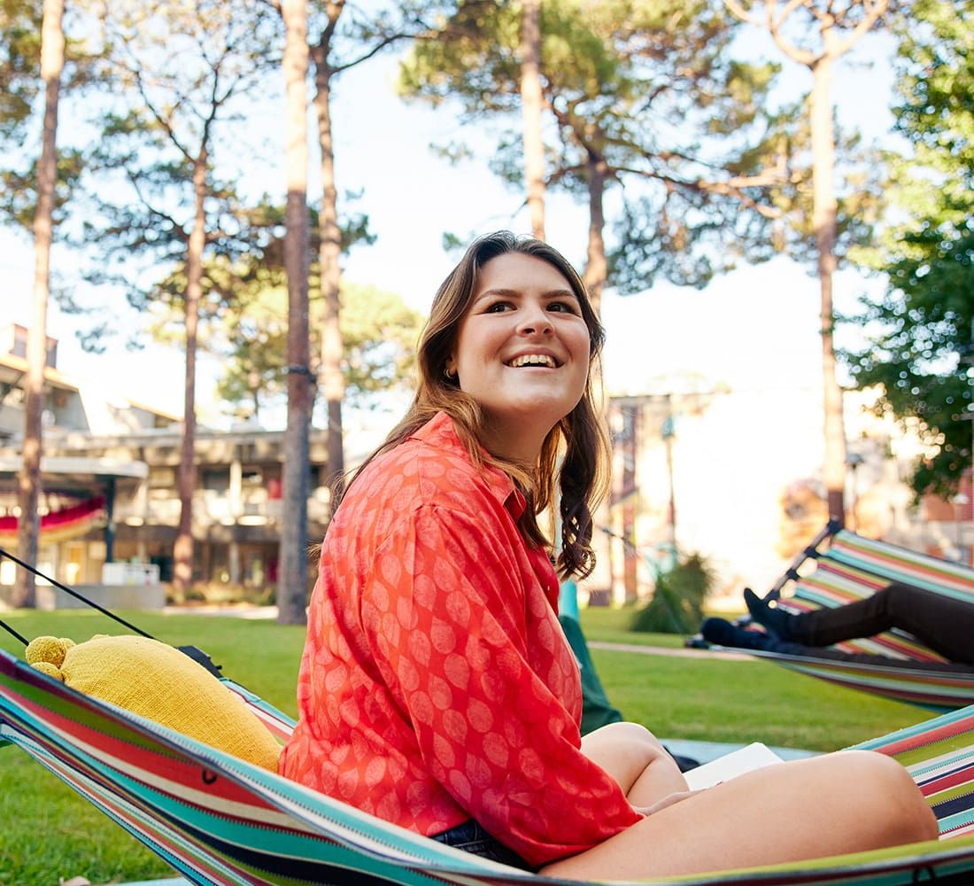 Young female student sitting on grassed area