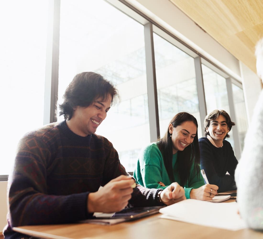 group of happy students sitting at a table and completing forms