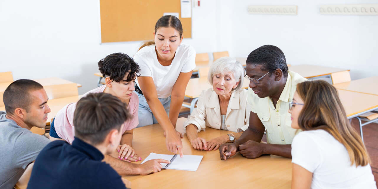 Student group and tutor at a classroom table.