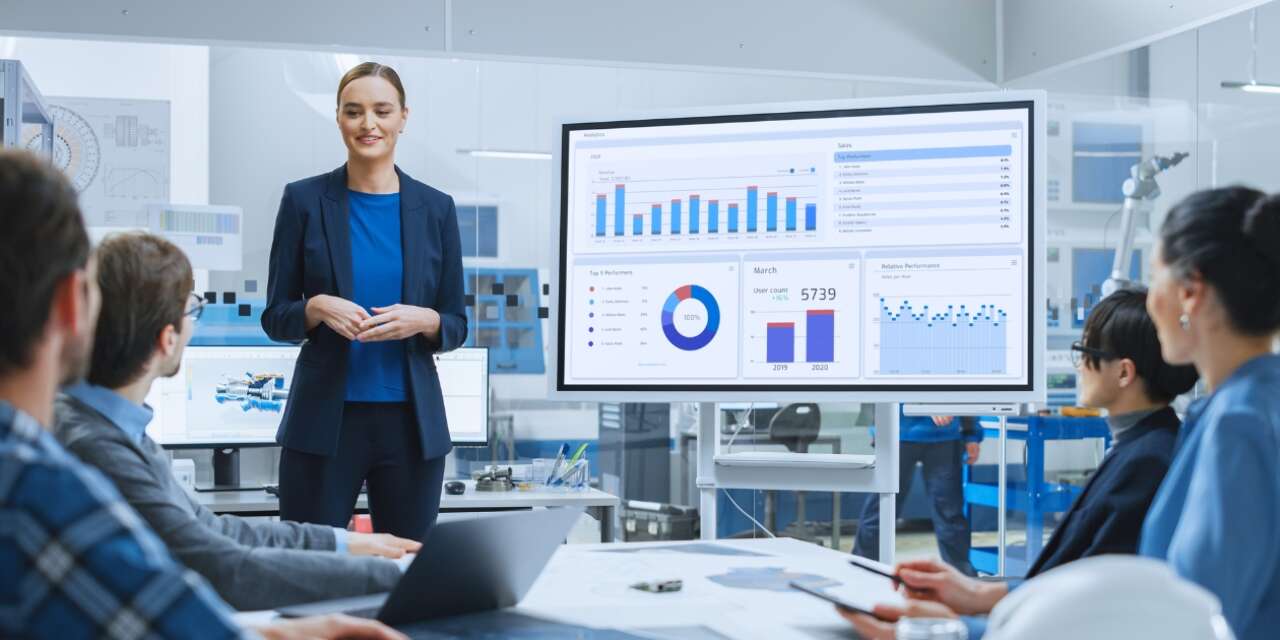 A group of young professionals study a display of analytics