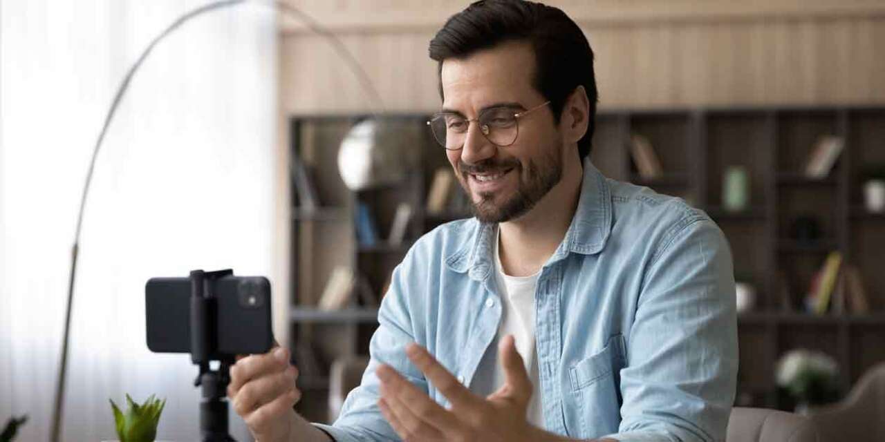 Man looks into mobile phone set on a tripod.